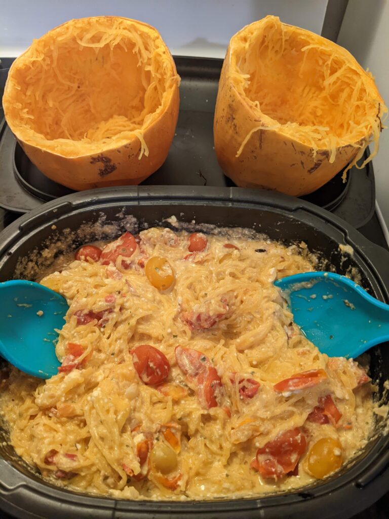 Tik Tok pasta made with spaghetti squash and boursin in a Tupperware UltraPro casserole dish with the empty spaghetti squash shells in the background