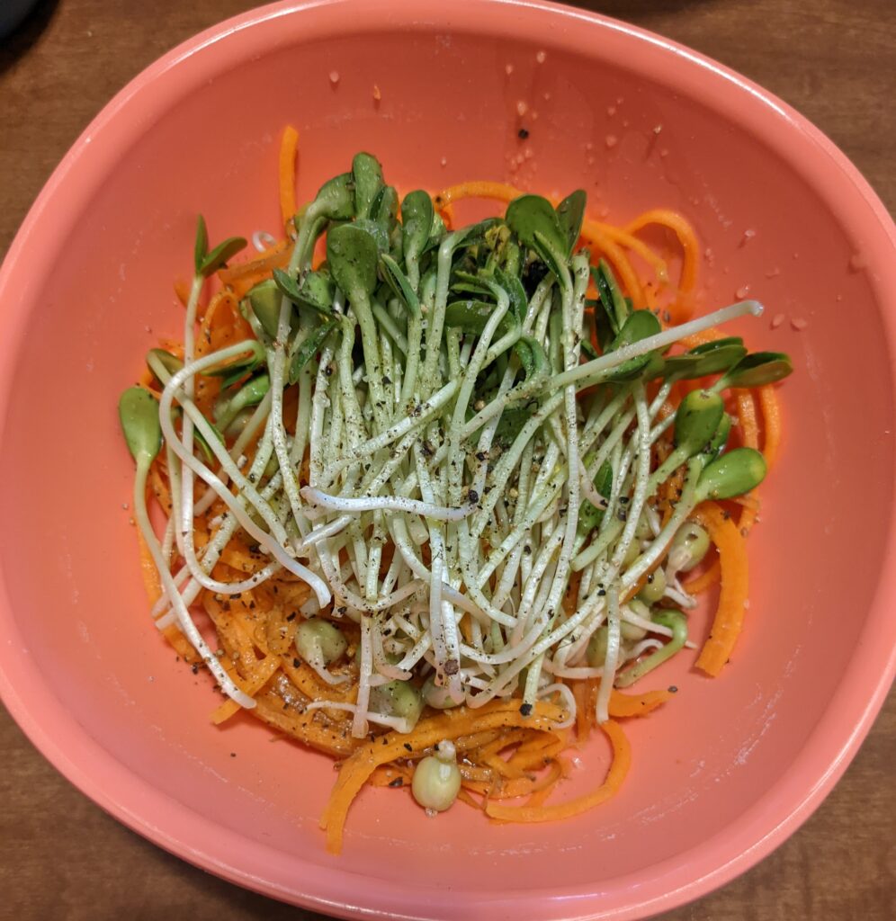 sunflower microgreens topping a carrot salad in a bowl