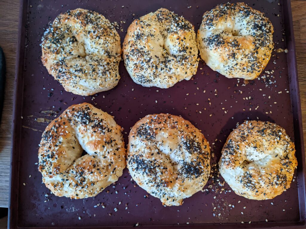 6 bagels with everything bagel topping on a Tupperware silicone baking sheet.