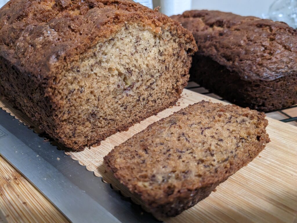 two loaves of the best banana bread ever, once with the end sliced so you can see the inside of the loaf.