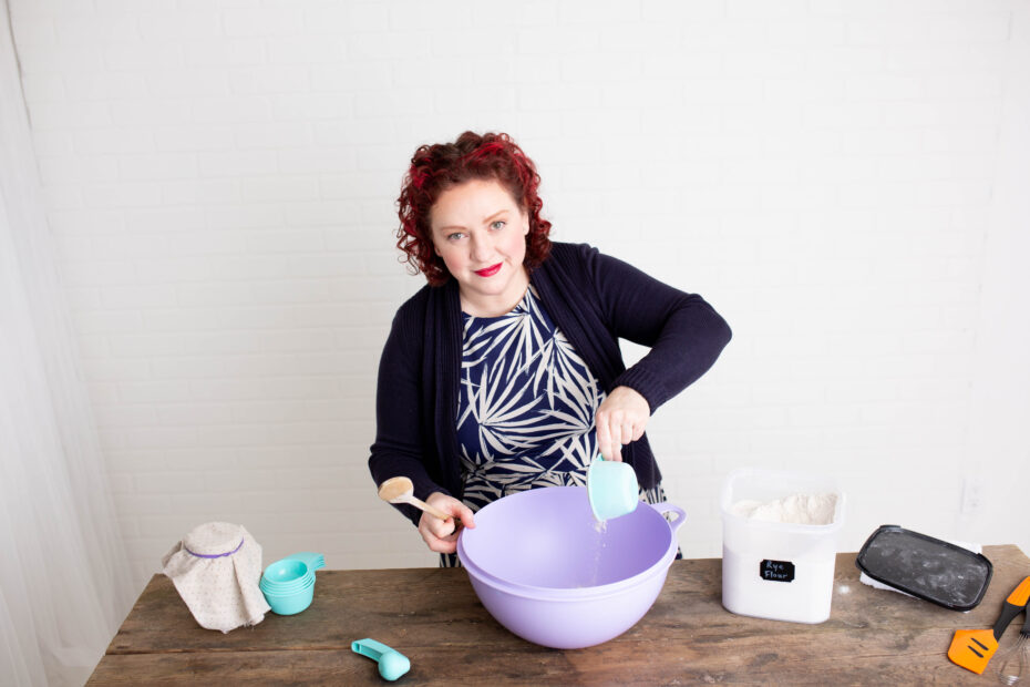 image of Heather O'Shea making the dough for sourdough bread on a wooden countertop.