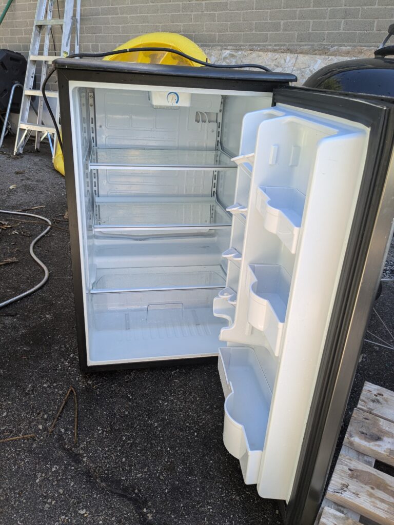 small fridge with the door open revealing three shelves and one drawer inside